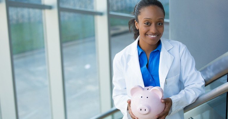 Woman in lab coat holding piggy bank