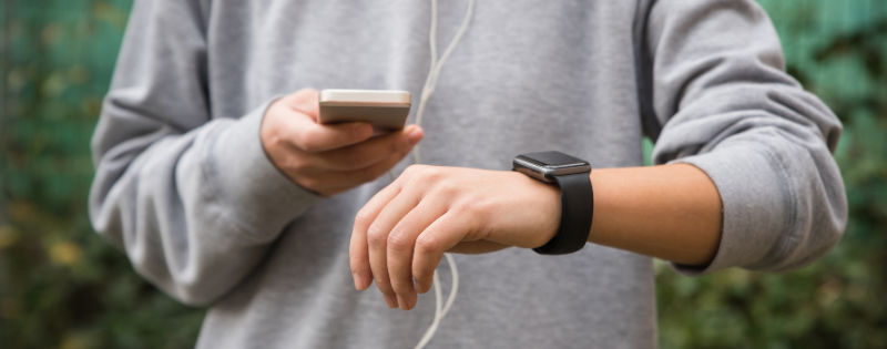 individual wearing a watch looking at a phone with earbuds