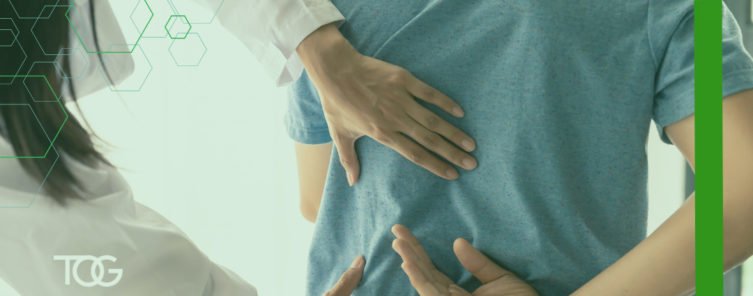 Patient in blue shirt experiencing pain being supported by a health care worker.