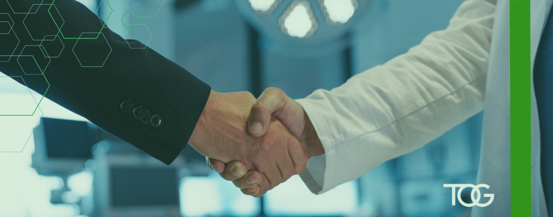 Business executive and doctor shaking hands in a hospital setting.