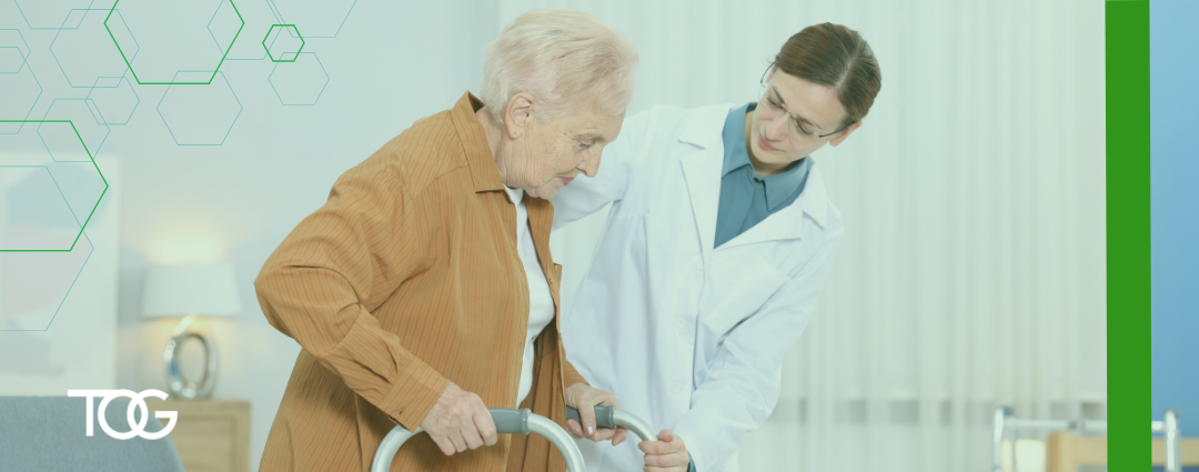Young female doctor wearing a white coat helps an elderly female patient with her walker.