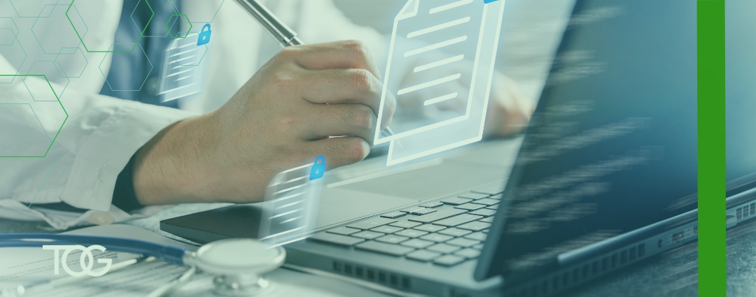 Health care professional writing beside a laptop and stethoscope, with digital document and lock icons representing secure medical records and data.